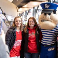 Three alumnae pose with Louie the Laker at the Detroit Red Wings GVSU Night